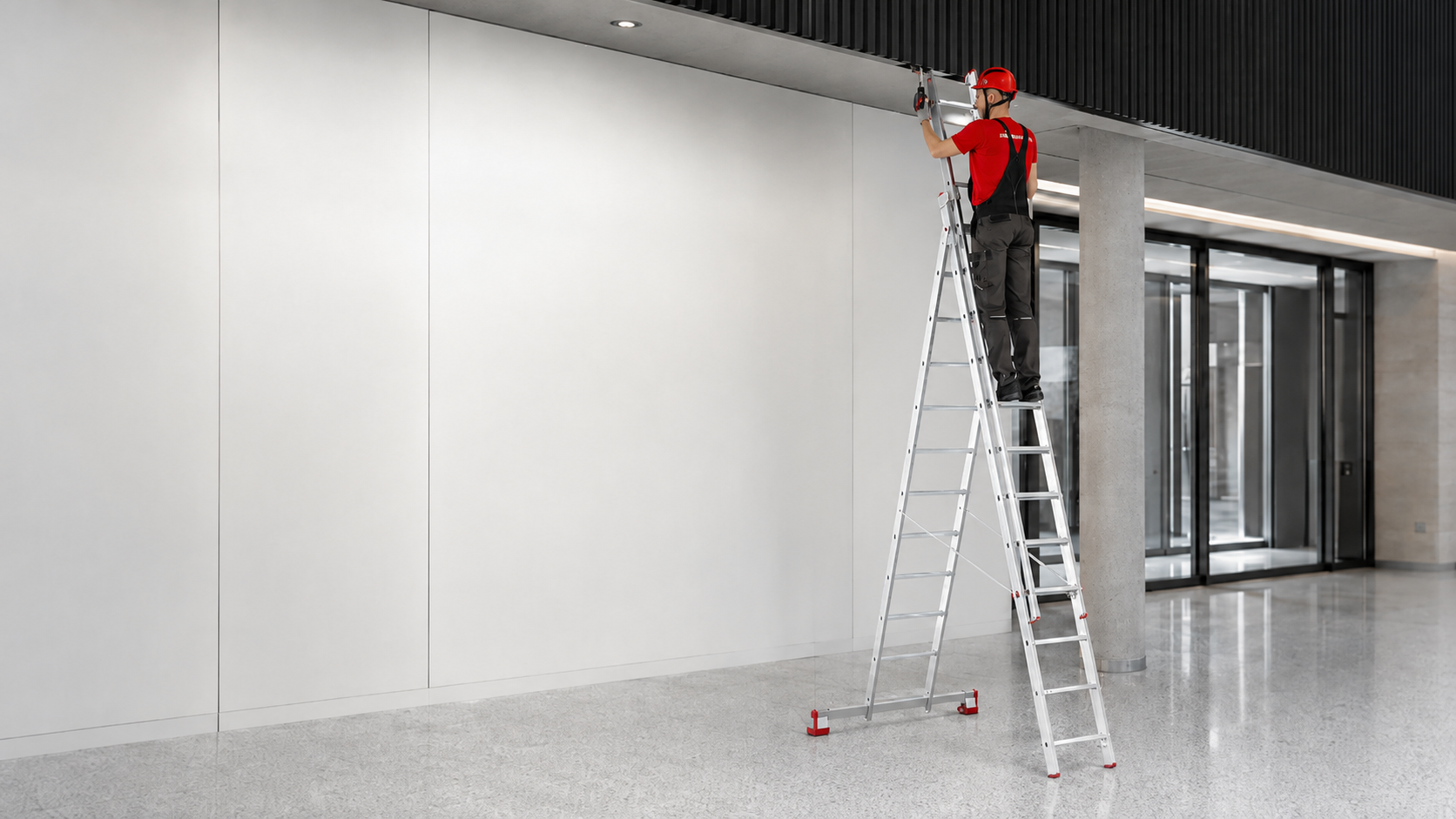 pracownik na drabinie aluminiowej 3-elementowej pracujący pod sufitem w warszawie